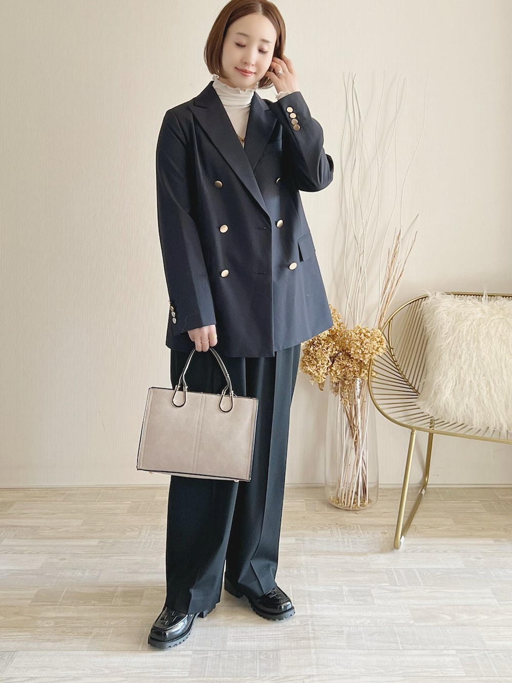 ブルー系のテーラードジャケット、ブラウン系のパンツ、ブラック系のバッグを着用したレディースの秋コーディネートの2枚目の写真