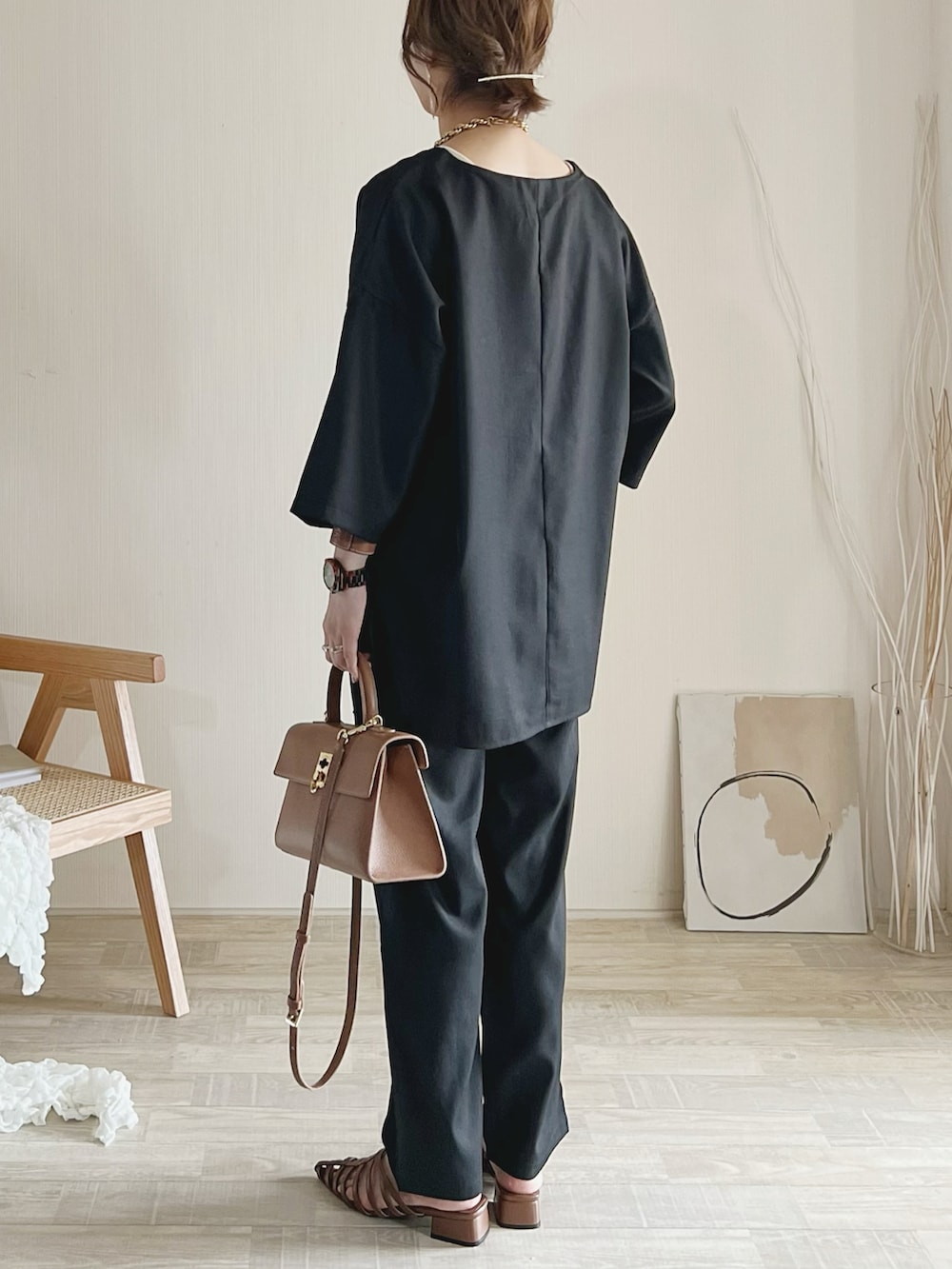 ブラック系のセットアップ、ブラウン系のサンダル、ブラウン系のバッグを着用したレディースの夏コーディネートの2枚目の写真