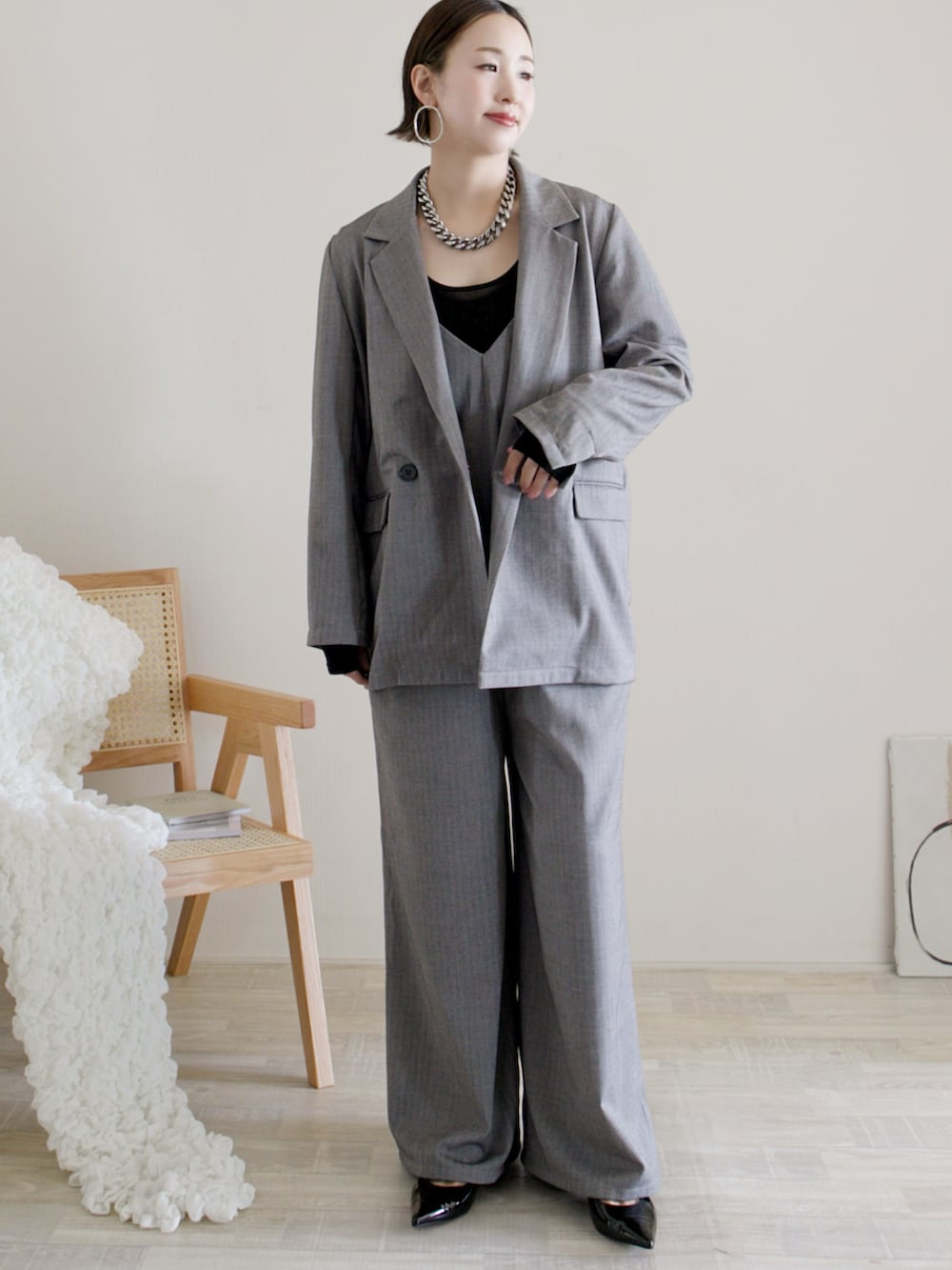 グレー系のテーラードジャケット、グレー系のワンピース、ブラック系のパンプスを着用したレディースの冬コーディネートの2枚目の写真