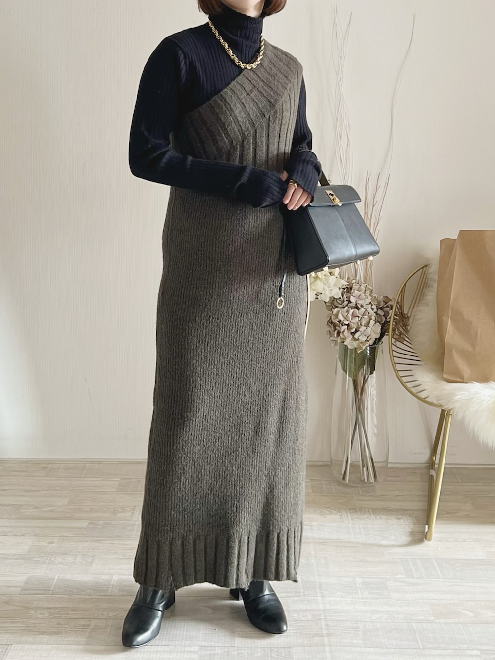 グリーン系のワンピース、ブラック系のニット/セーター、ブラック系のバッグを着用したレディースの冬コーディネートの2枚目の写真