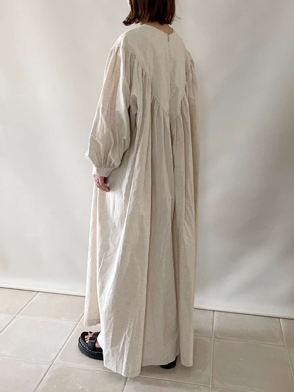 ベージュ系のワンピース、ベージュ系のかごバッグ、ブラック系のサンダルを着用したレディースの春コーディネートの4枚目の写真