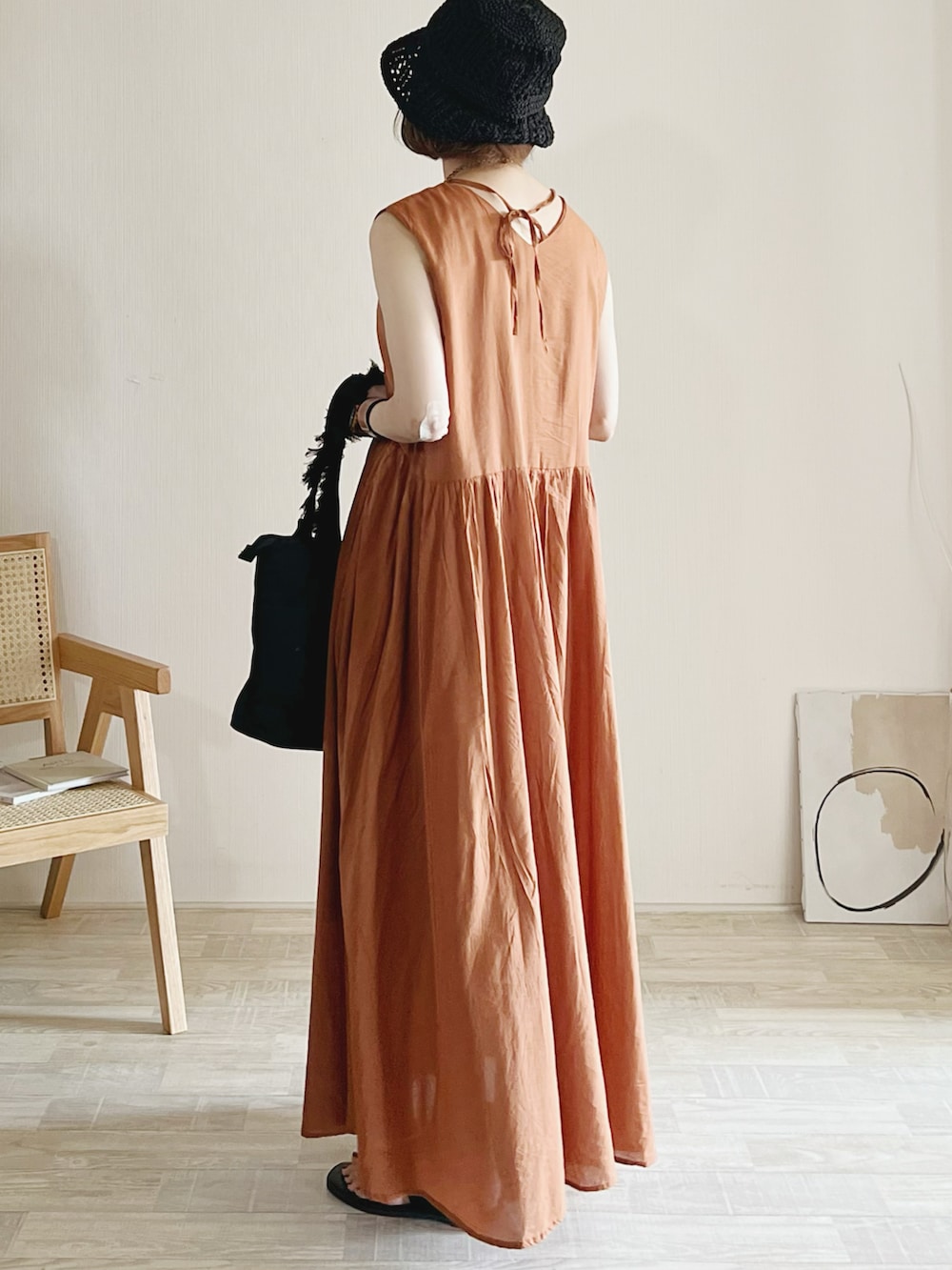 オレンジ系のワンピース、ブラック系のトートバッグ、ブラック系のサンダルを着用したレディースの夏コーディネートの2枚目の写真