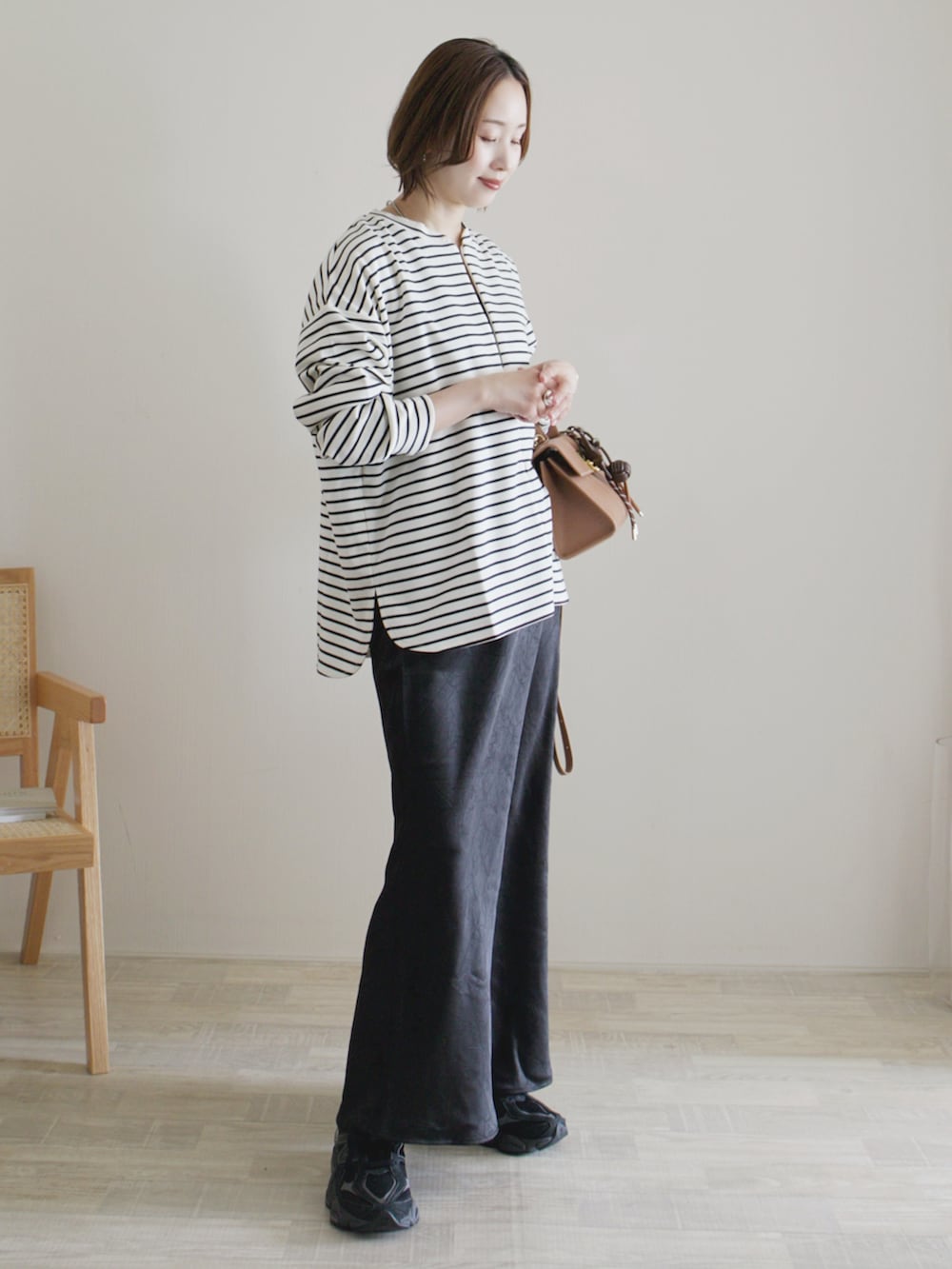 ホワイト系のTシャツ/カットソー、ブラック系のスカート、ブラック系のスニーカーを着用したレディースの春コーディネートの2枚目の写真