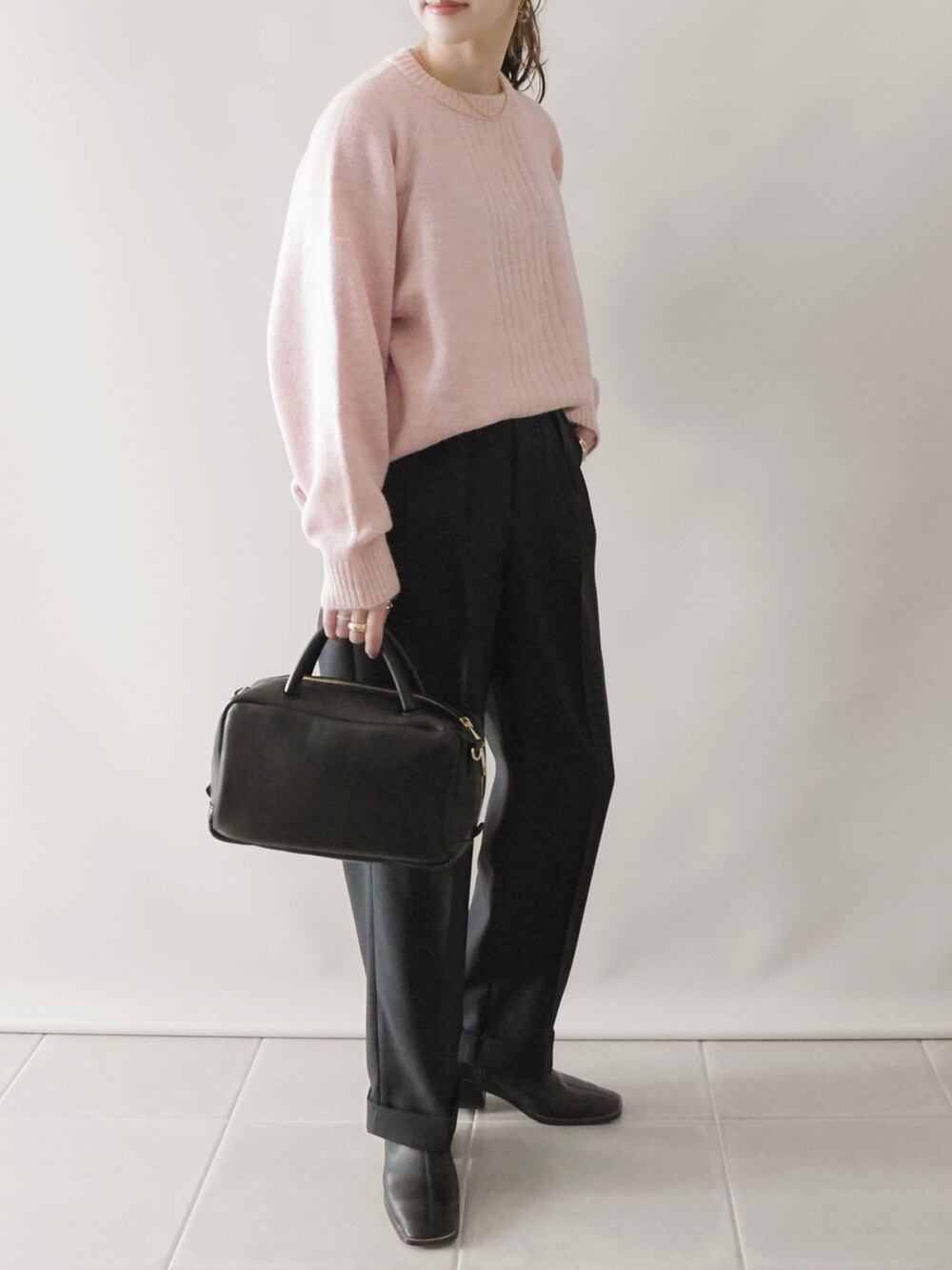 ピンク系のニット/セーター、ブラック系のその他パンツ、ブラック系のボストンバッグを着用したレディースの冬コーディネートの2枚目の写真