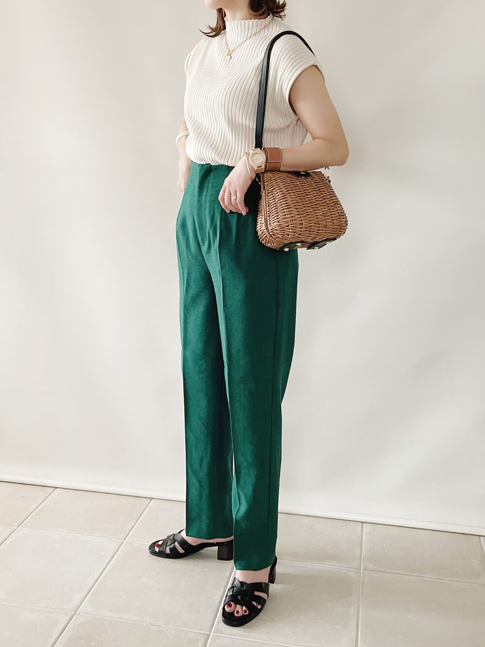 グリーン系のその他パンツ、ホワイト系のニット/セーター、ブラウン系のかごバッグを着用したレディースの春コーディネートの2枚目の写真