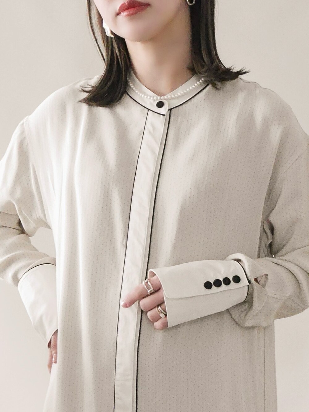 グレー系のステンカラーコート、ホワイト系のワンピース、グレー系のバッグを着用したレディースの冬コーディネートの3枚目の写真