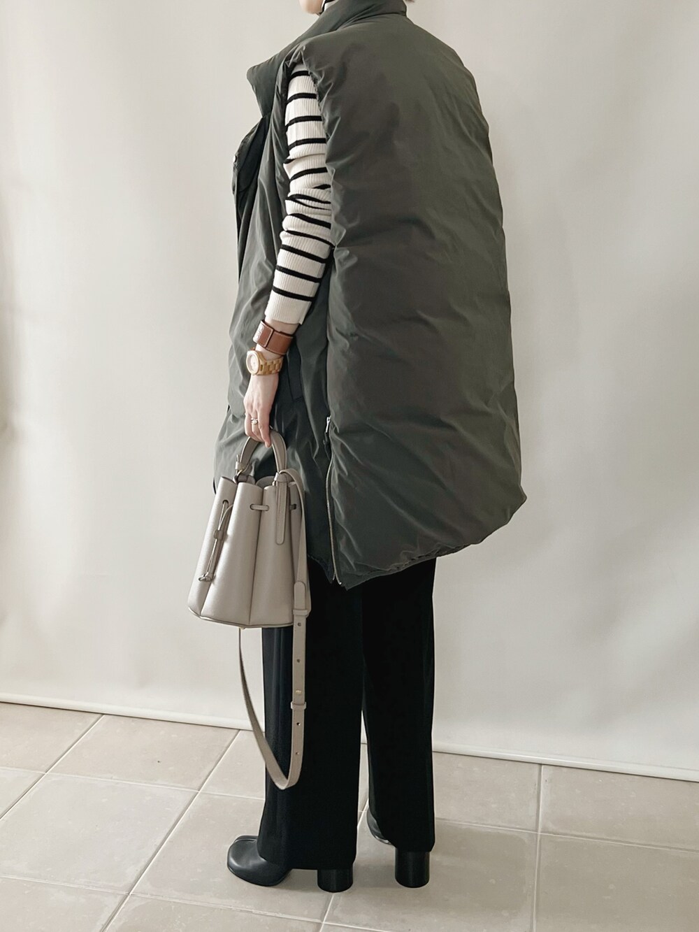 ホワイト系のトップス、グリーン系のダウンベスト、ブラウン系のパンツを着用したレディースの秋コーディネートの3枚目の写真