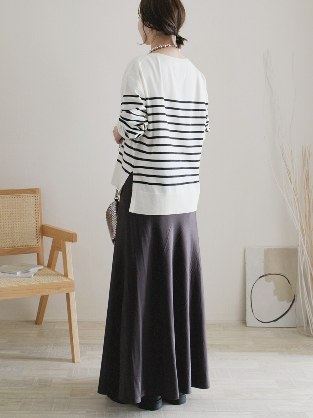 ホワイト系のニット/セーター、グレー系のスカート、グレー系のハンドバッグを着用したレディースの秋コーディネートの2枚目の写真