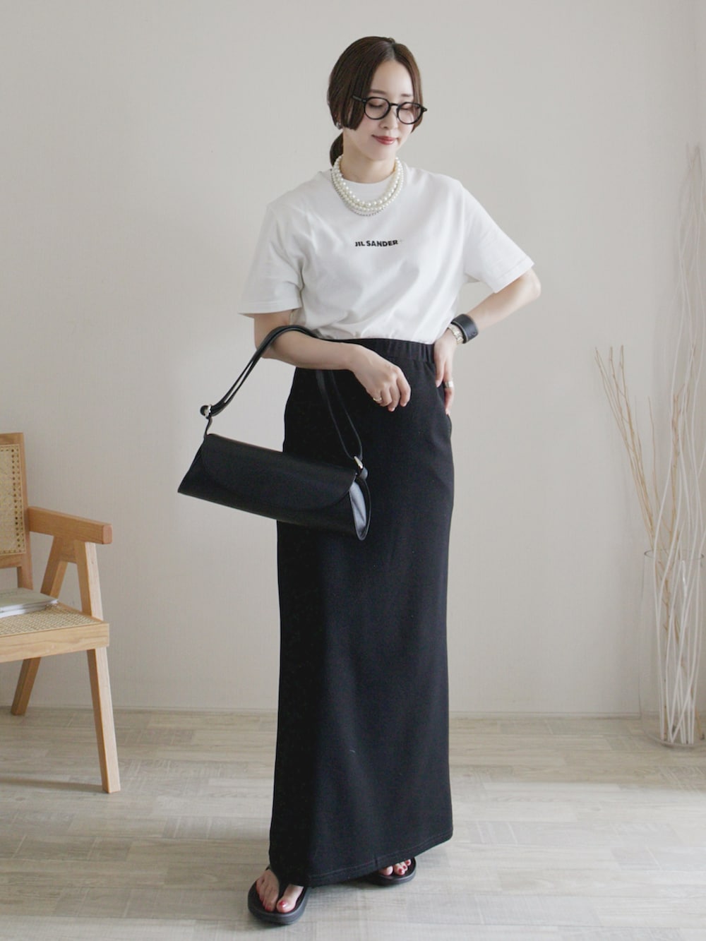 ベージュ系のTシャツ/カットソー、ブラック系のスカート、ブラック系のサンダルを着用したレディースの夏コーディネートの2枚目の写真