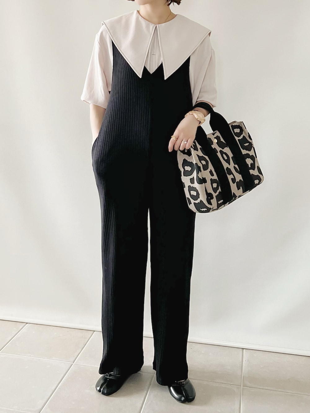 ブラック系のオールインワン・サロペット、ベージュ系のトップス、ベージュ系のトートバッグを着用したレディースの夏コーディネートの3枚目の写真