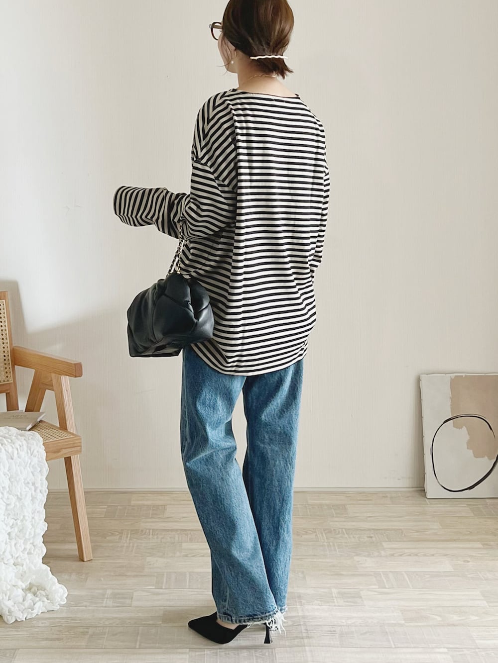 ベージュ系のTシャツ/カットソー、ブラック系のクラッチバッグ、ブルー系のデニムパンツを着用したレディースの秋コーディネートの3枚目の写真