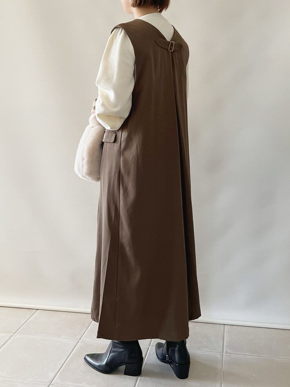 ブラウン系のジャンパースカート、ホワイト系のカーディガン/ボレロ、ホワイト系のバッグを着用したレディースの秋コーディネートの4枚目の写真