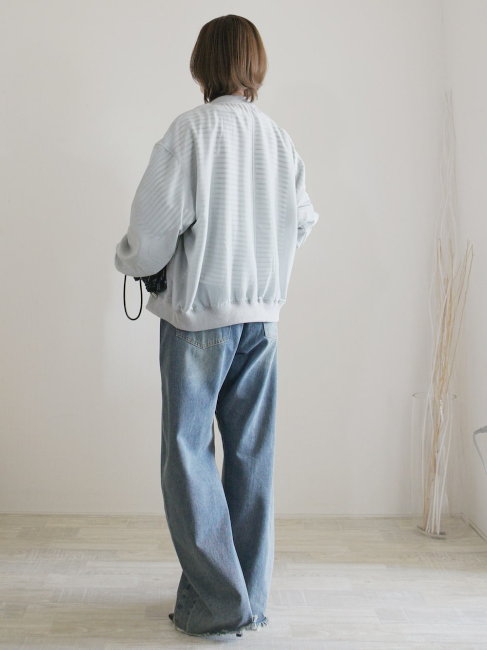 ブルー系のデニムパンツ、ブラック系のパンプス、ブラック系のクラッチバッグを着用したレディースの春コーディネートの2枚目の写真