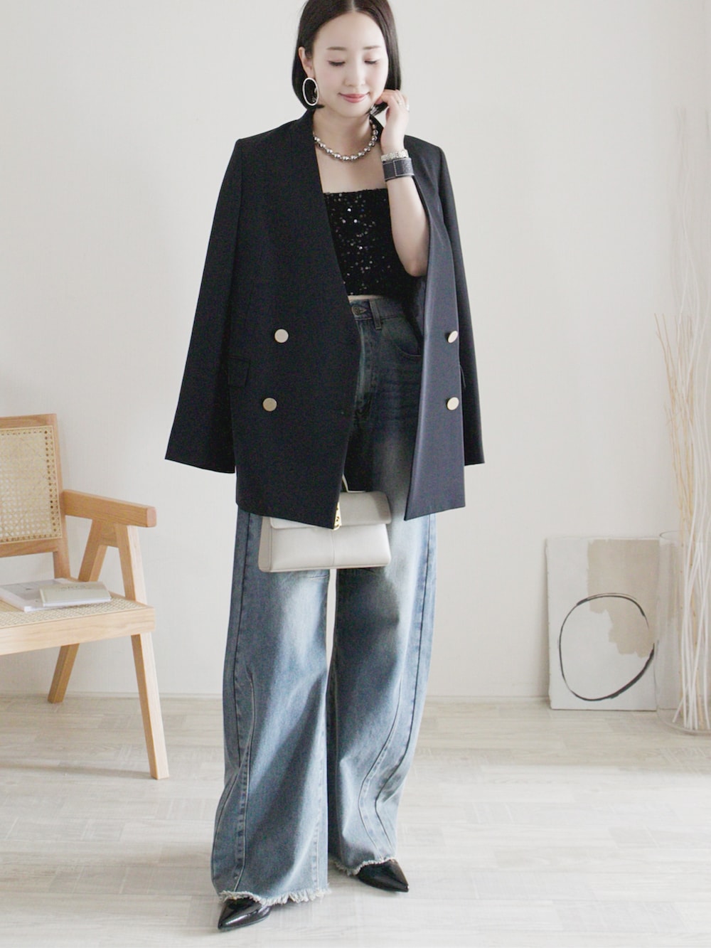 ブラック系のノーカラージャケット、ブラック系のチューブトップ、ブルー系のデニムパンツを着用したレディースの夏コーディネートの2枚目の写真