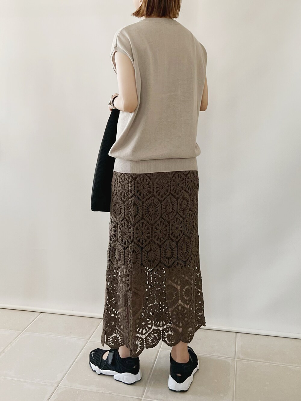 ベージュ系のTシャツ/カットソー、ブラウン系のスカート、ブラック系のハンドバッグを着用したレディースの夏コーディネートの3枚目の写真