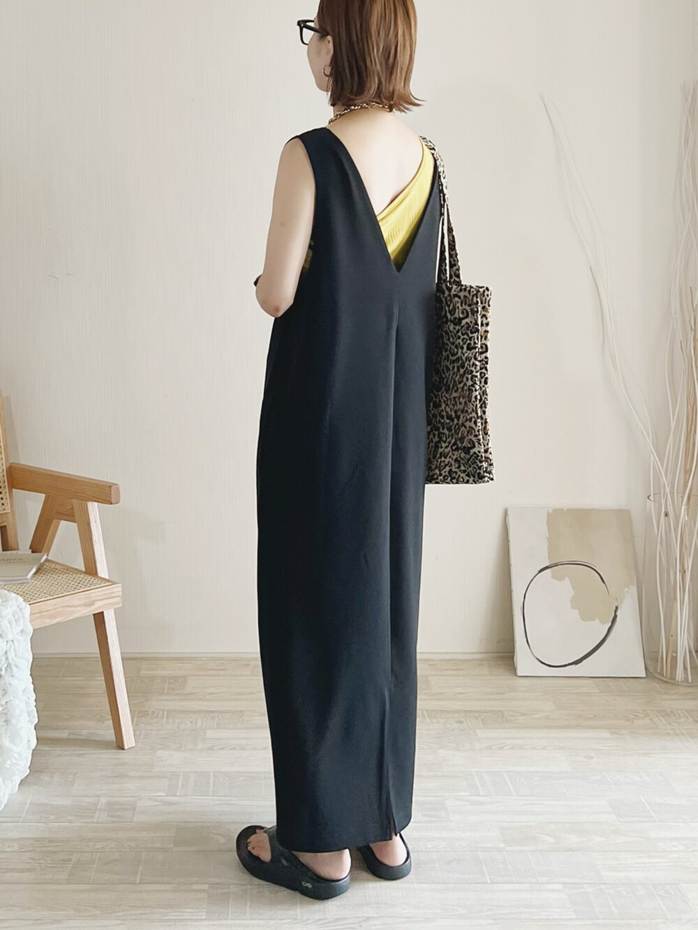 ブラック系のワンピース、イエロー系のトップス、ベージュ系のトートバッグを着用したレディースの夏コーディネートの2枚目の写真