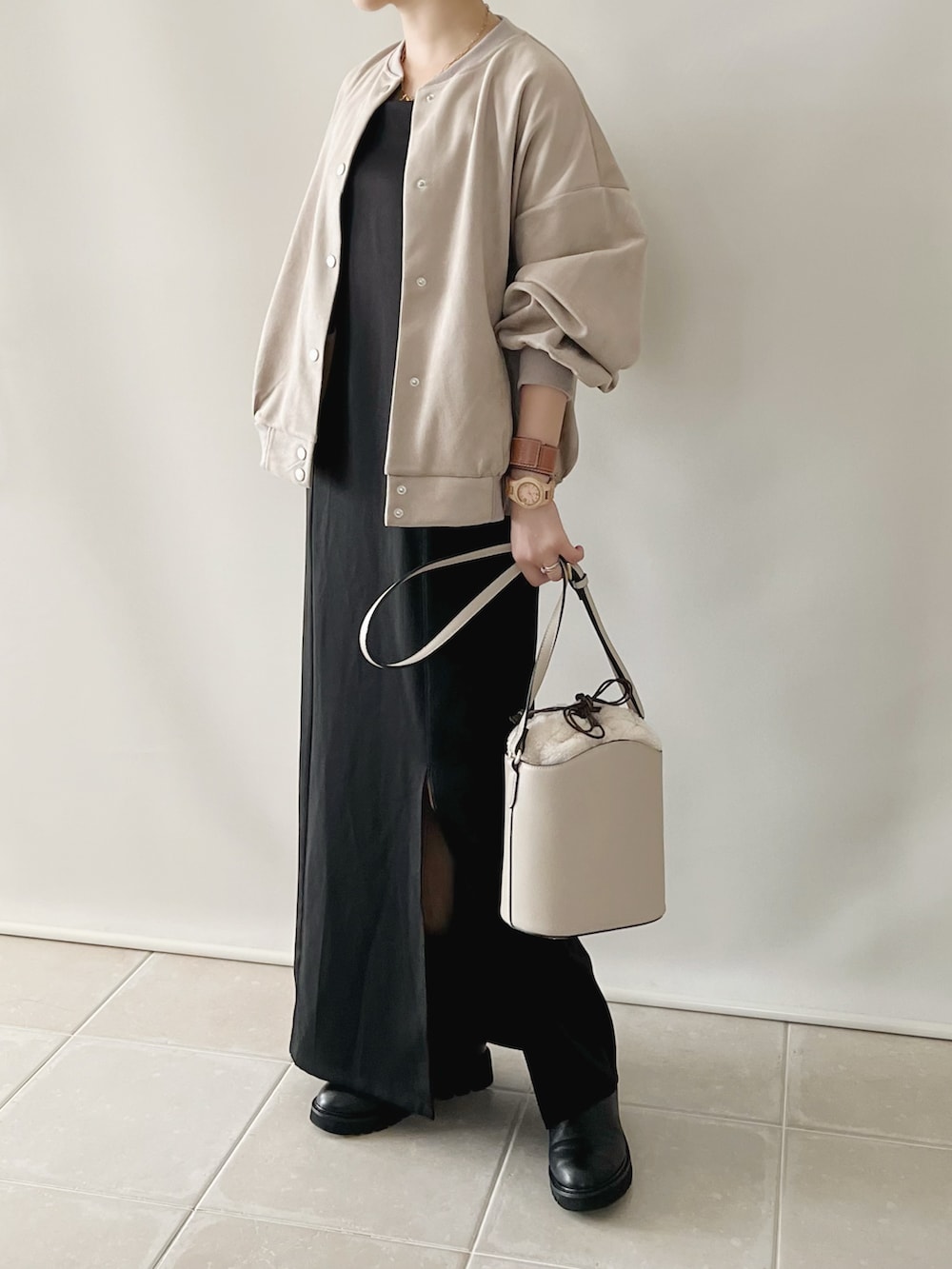 ブラック系のワンピース、ベージュ系のスタジャン、ホワイト系のバッグを着用したレディースの秋コーディネートの2枚目の写真