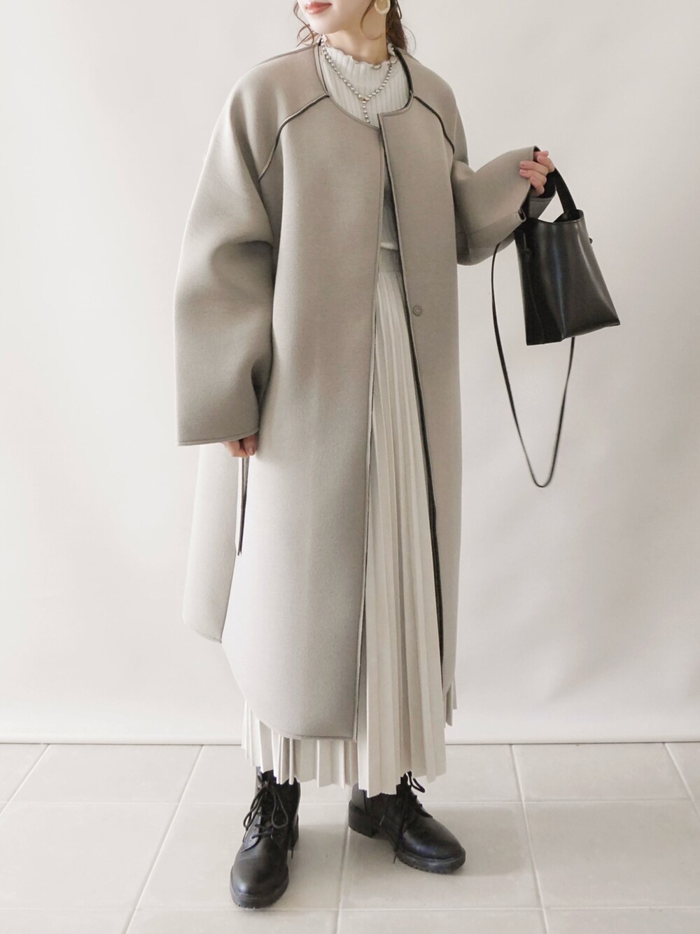 グレー系のノーカラーコート、ホワイト系のTシャツ/カットソー、ブラック系のボストンバッグを着用したレディースの秋コーディネートの3枚目の写真