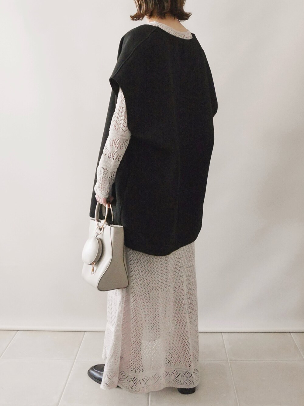 ベージュ系のワンピース、ブラック系のトップス、ベージュ系のバッグを着用したレディースの春コーディネートの3枚目の写真