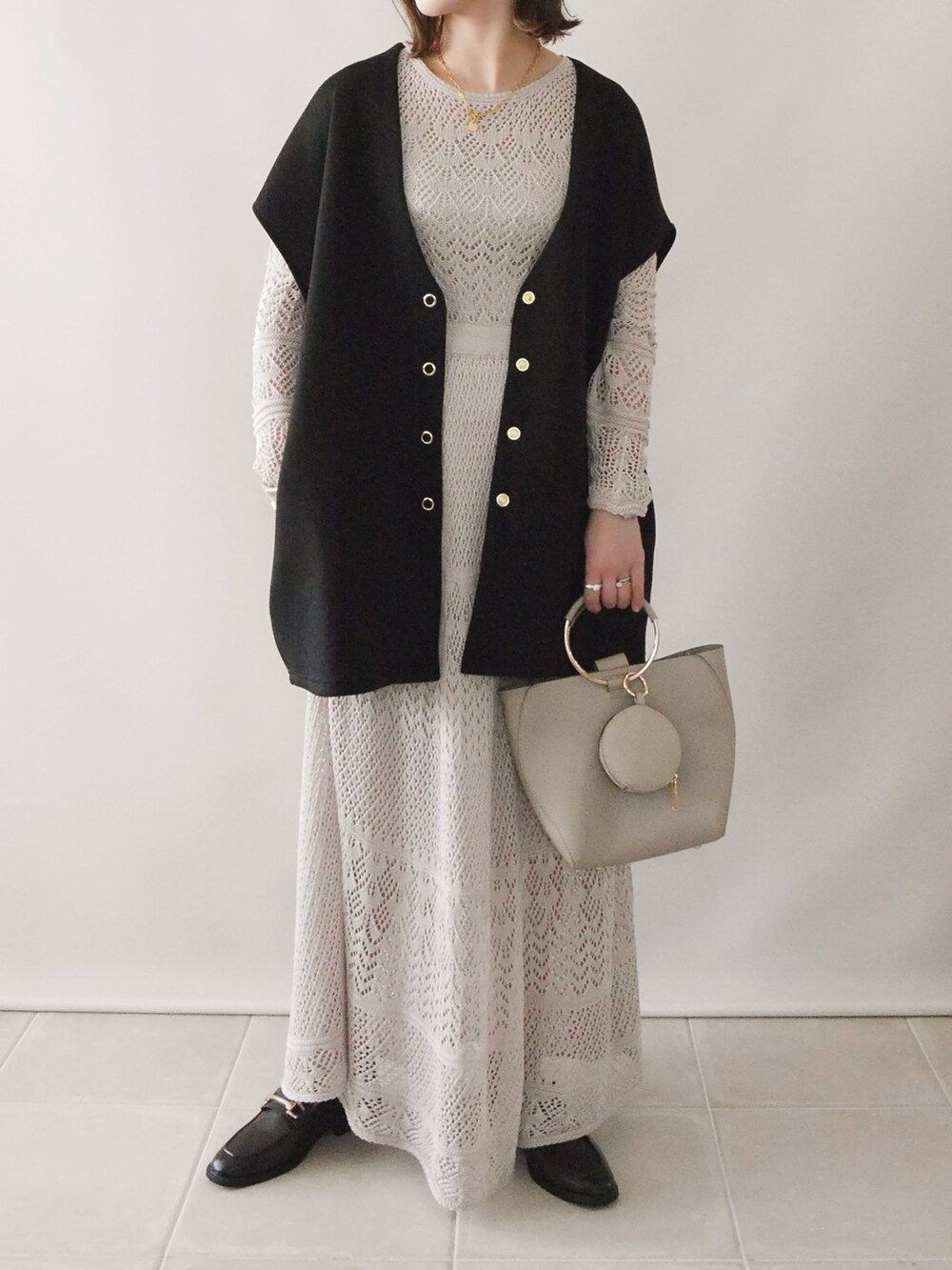 ベージュ系のワンピース、ブラック系のトップス、ベージュ系のバッグを着用したレディースの春コーディネートの2枚目の写真