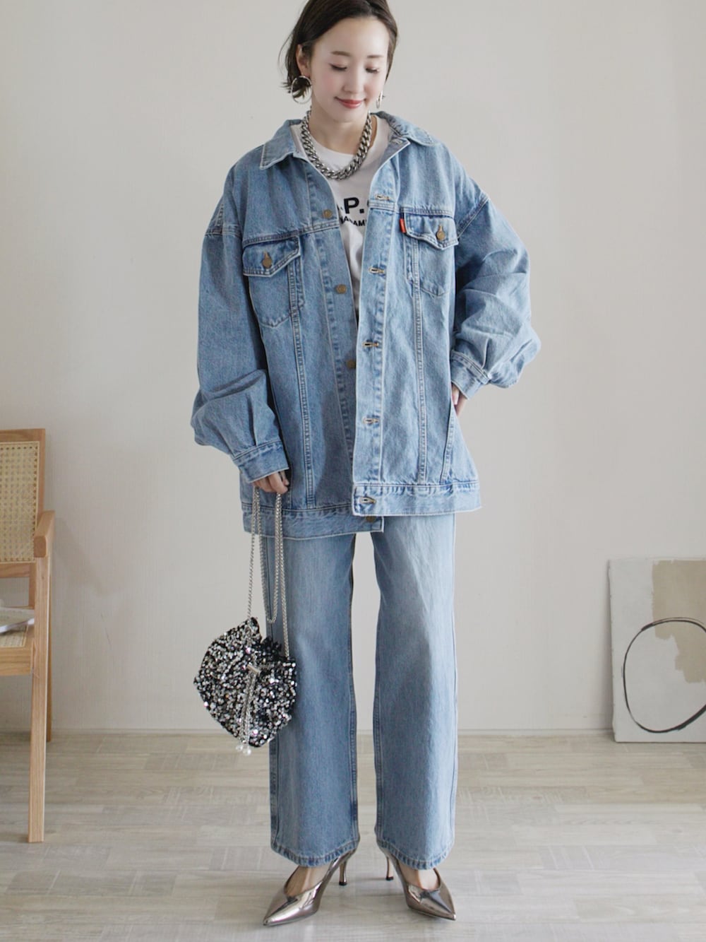 ブルー系のデニムジャケット、ブルー系のデニムパンツ、シルバー系のショルダーバッグを着用したレディースの冬コーディネートの2枚目の写真