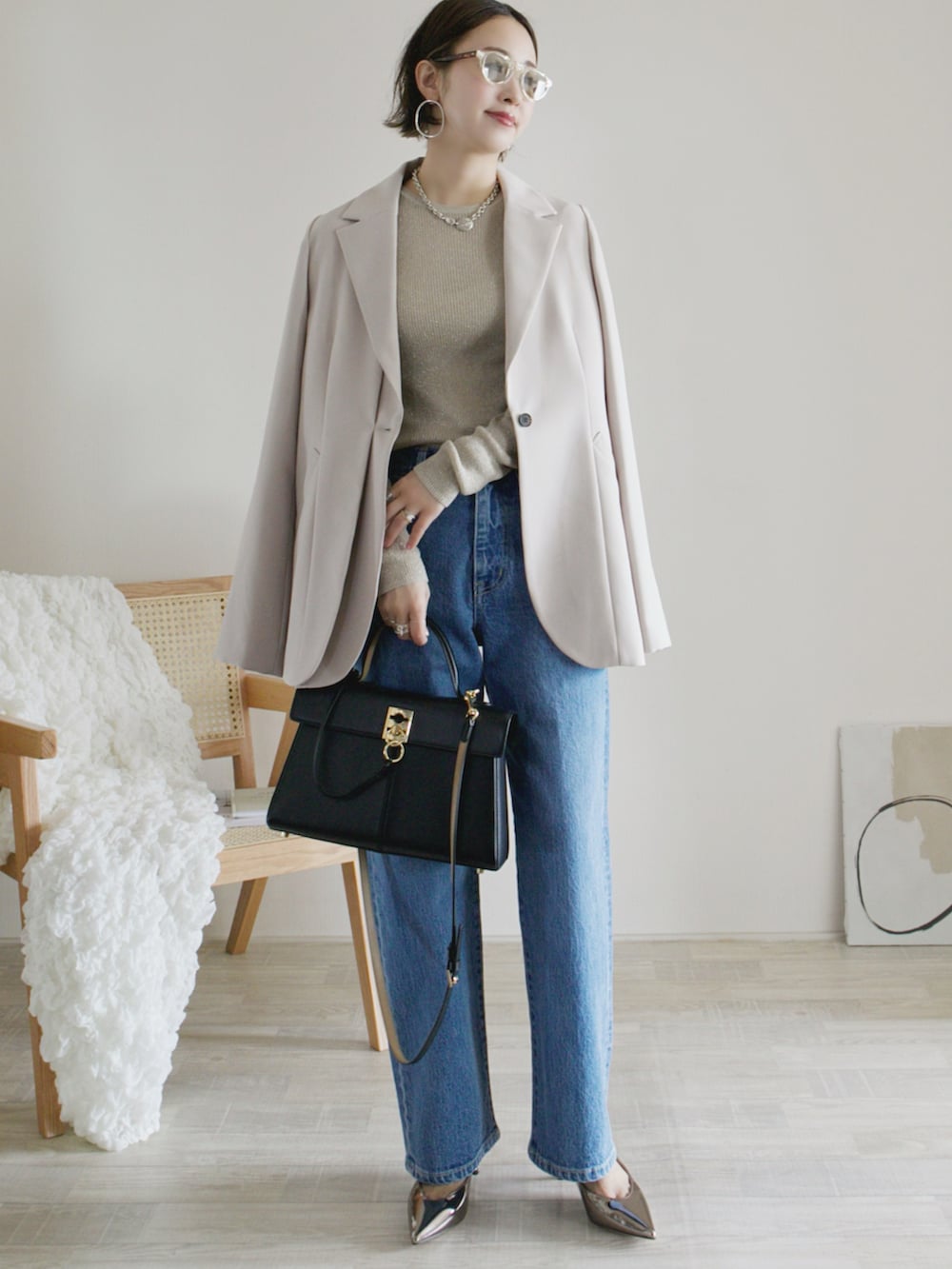 ベージュ系のテーラードジャケット、ベージュ系のニット/セーター、ブルー系のデニムパンツを着用したレディースの冬コーディネートの2枚目の写真