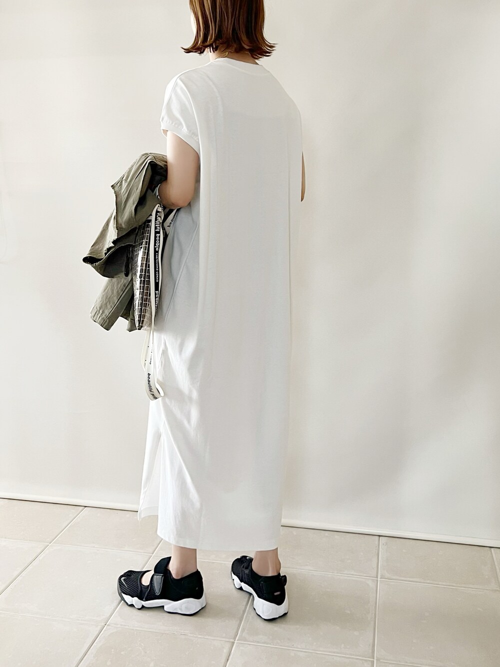 ホワイト系のワンピース、ブラック系のショルダーバッグ、ブルー系のデニムパンツを着用したレディースの夏コーディネートの5枚目の写真