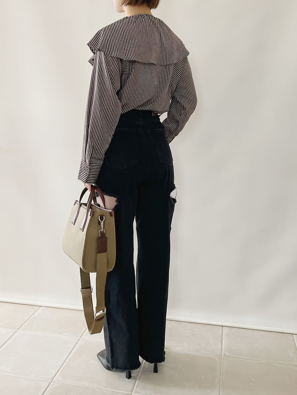 ブルー系のシャツ/ブラウス、ブラック系のデニムパンツ、ベージュ系のバッグを着用したレディースの秋コーディネートの3枚目の写真