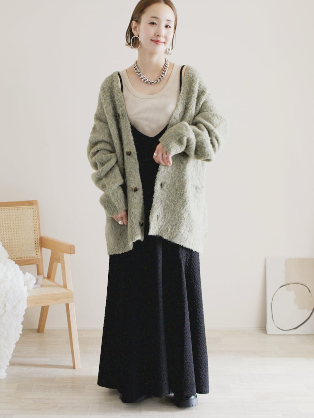 グリーン系のカーディガン/ボレロ、ブラック系のワンピース、ブラック系のシューズを着用したレディースの秋コーディネートの2枚目の写真