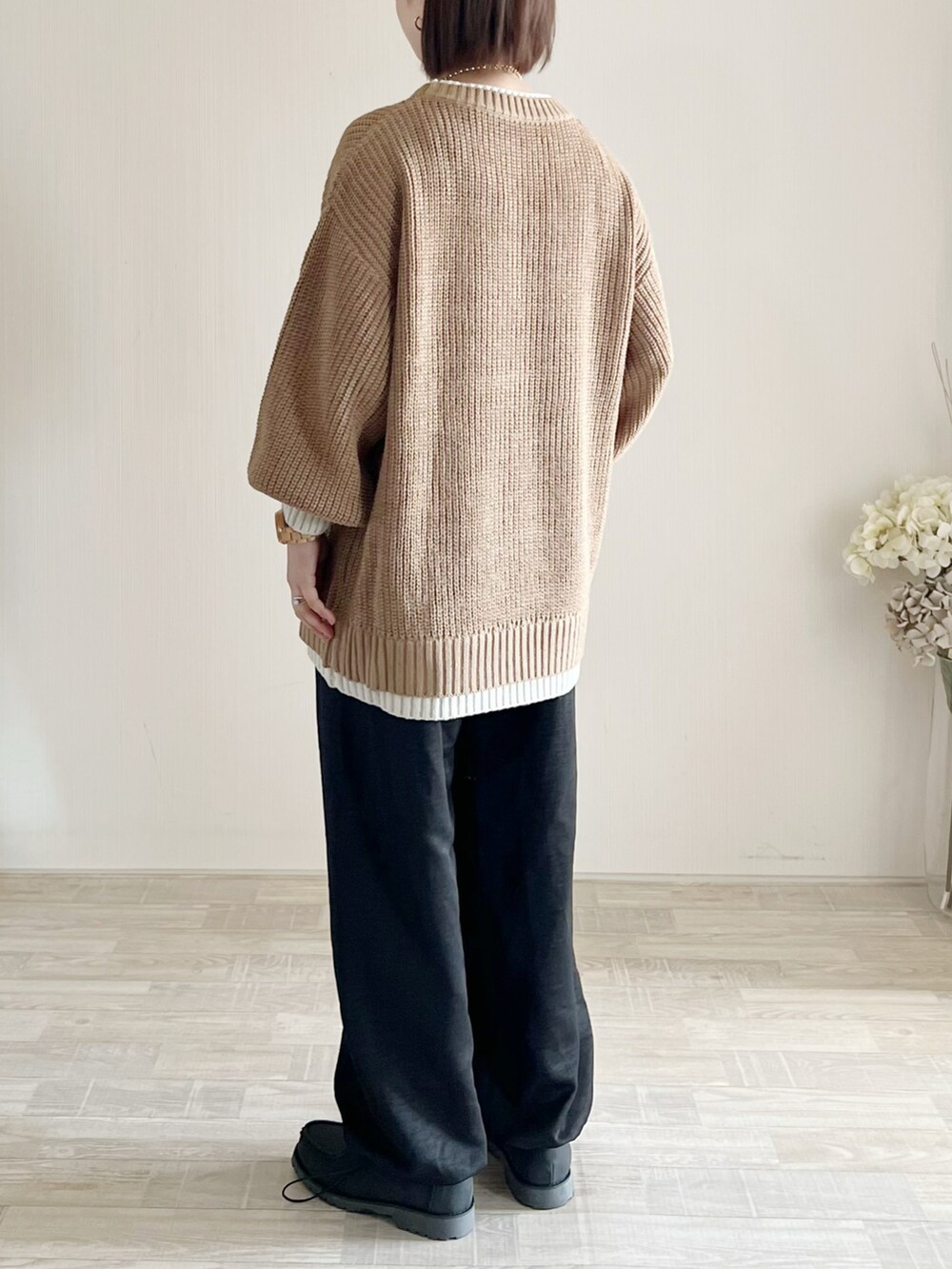 イエロー系のニット/セーター、ブラック系のパンツ、ホワイト系のシューズを着用したレディースの冬コーディネートの2枚目の写真