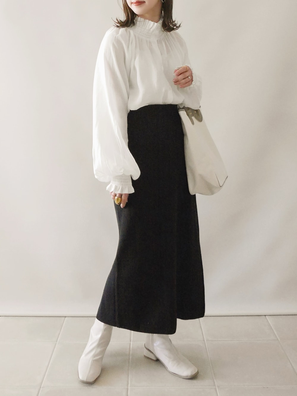 ベージュ系のトレンチコート、ホワイト系のシャツ/ブラウス、ブラック系のスカートを着用したレディースの春コーディネートの2枚目の写真