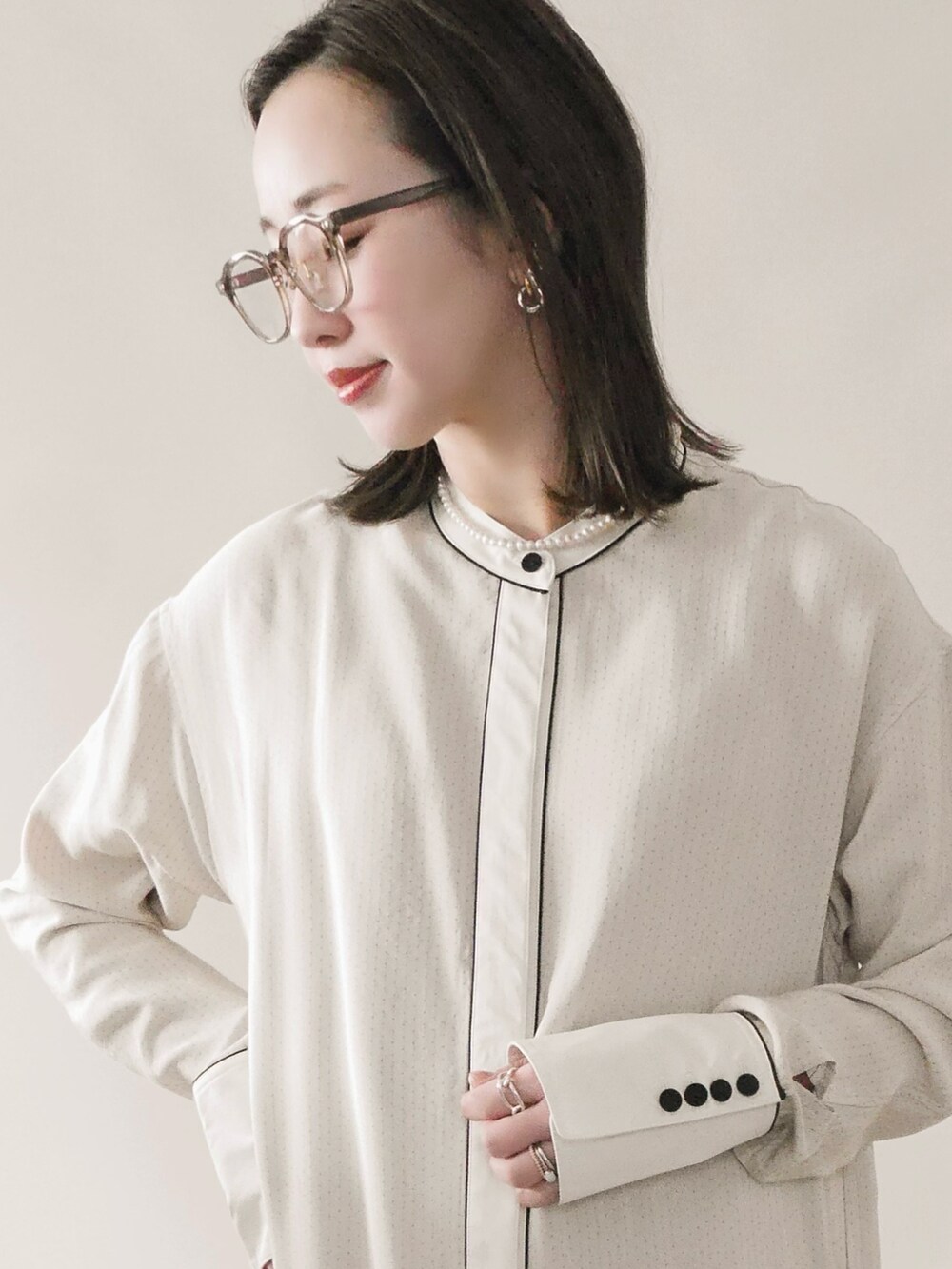 グレー系のステンカラーコート、ホワイト系のワンピース、グレー系のバッグを着用したレディースの冬コーディネートの2枚目の写真