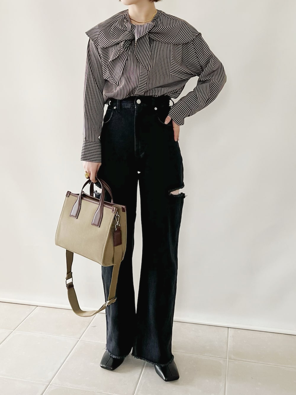 ブルー系のシャツ/ブラウス、ブラック系のデニムパンツ、ベージュ系のバッグを着用したレディースの秋コーディネートの4枚目の写真