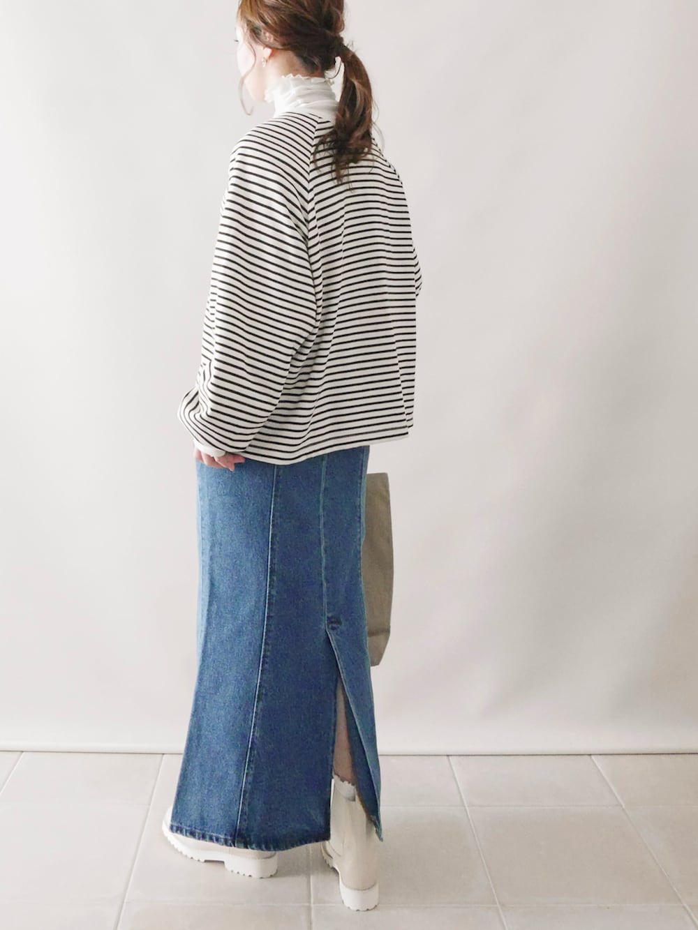 ホワイト系のトップス、ブルー系のデニムスカート、ベージュ系のブーツを着用したレディースの冬コーディネートの3枚目の写真