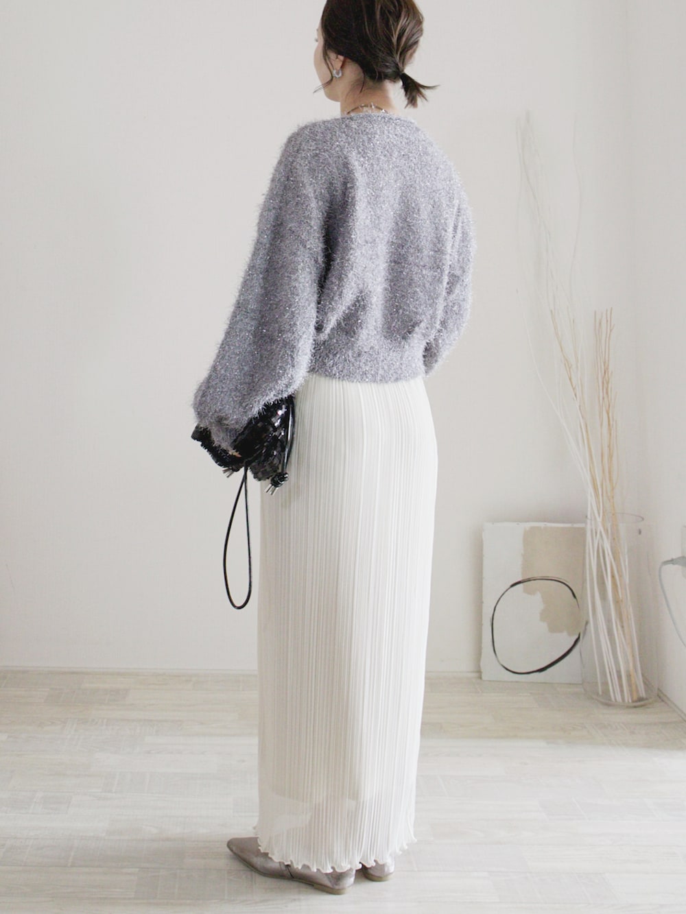 グレー系のニット/セーター、ホワイト系のスカート、ブラック系のクラッチバッグを着用したレディースの秋コーディネートの3枚目の写真
