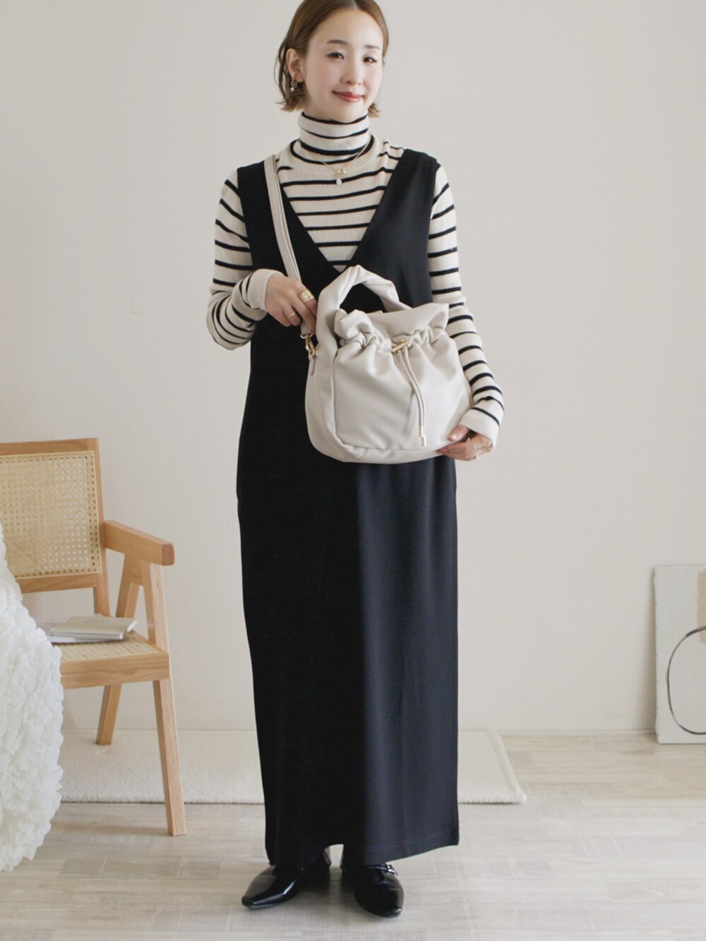 ブラック系のワンピース、ホワイト系のトップス、ブラック系のパンプスを着用したレディースの秋コーディネートの2枚目の写真