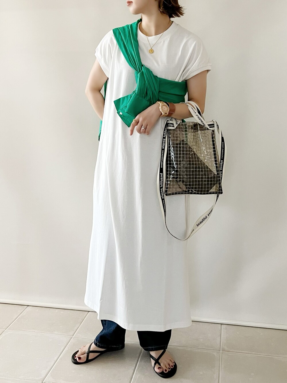 ホワイト系のワンピース、ブラック系のショルダーバッグ、ブルー系のデニムパンツを着用したレディースの夏コーディネートの2枚目の写真