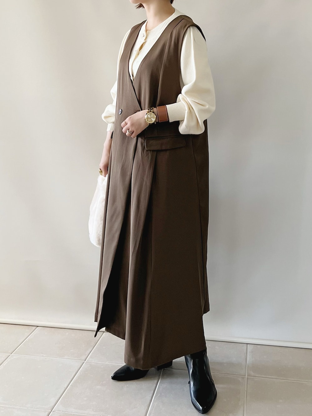 ブラウン系のジャンパースカート、ホワイト系のカーディガン/ボレロ、ホワイト系のバッグを着用したレディースの秋コーディネートの3枚目の写真