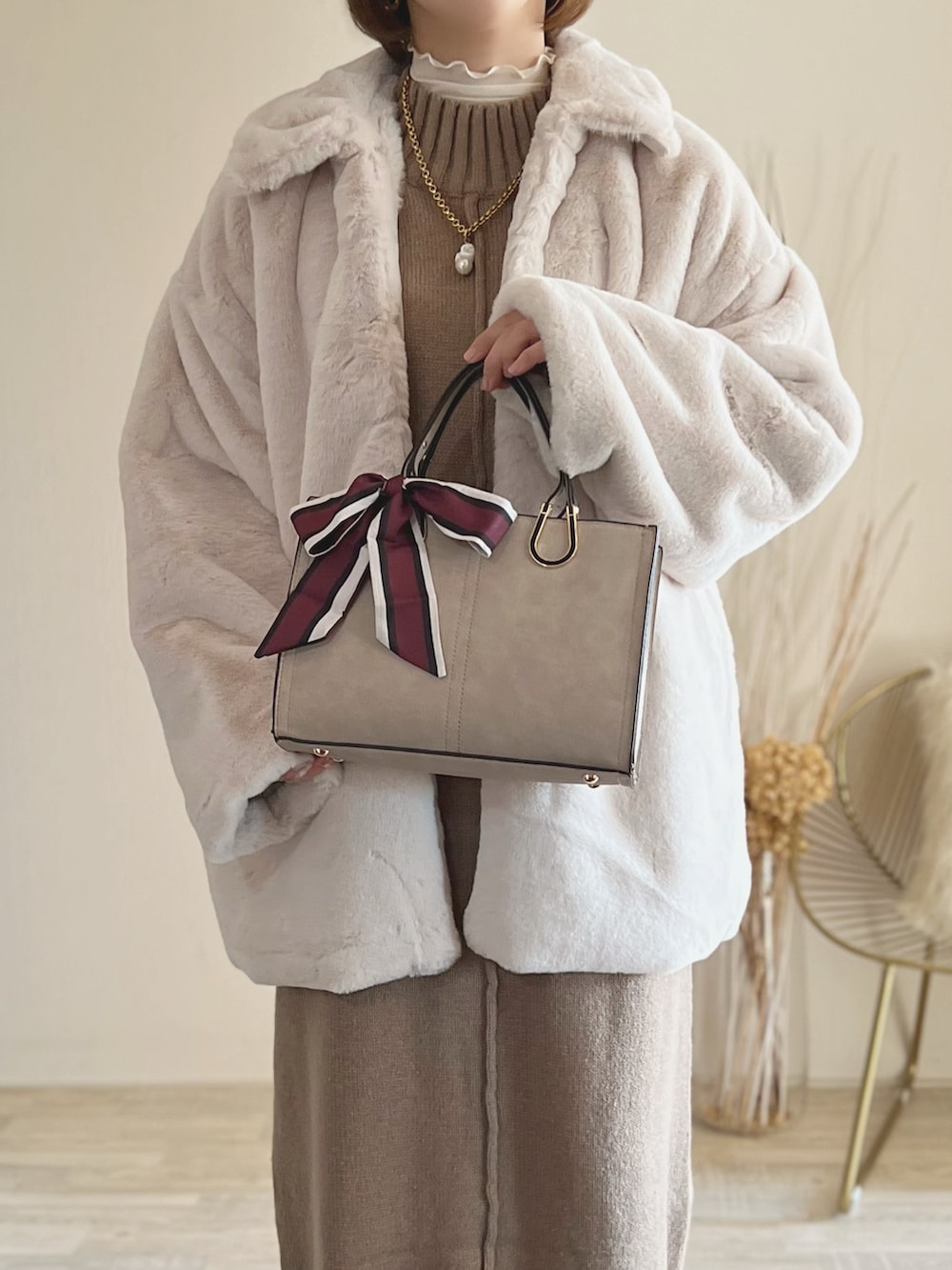 ホワイト系のステンカラーコート、ブラウン系のワンピース、ブラック系のバッグを着用したレディースの秋コーディネートの2枚目の写真