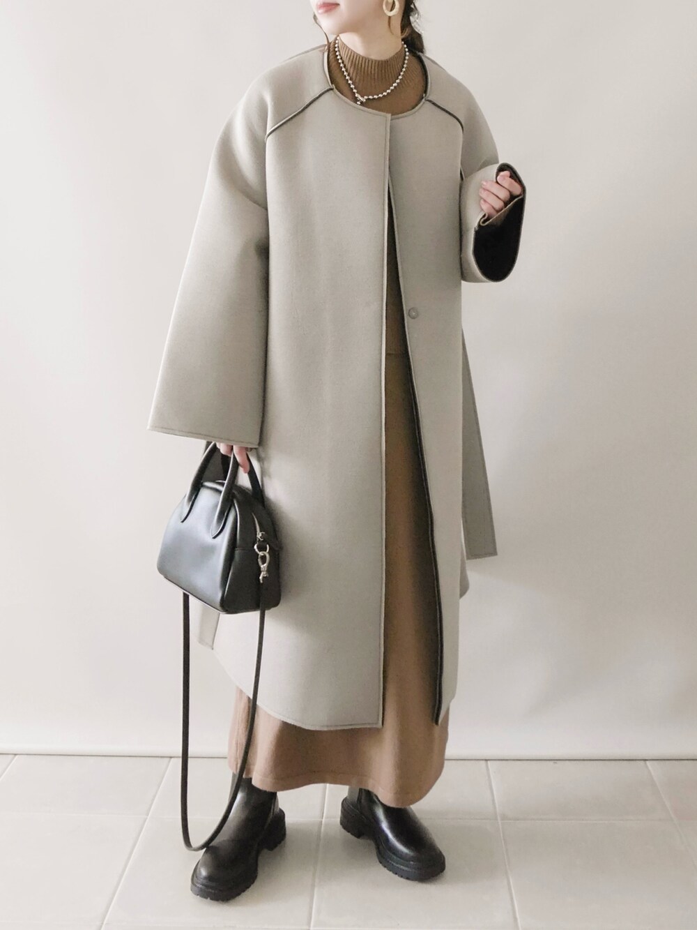 グレー系のノーカラーコート、ホワイト系のTシャツ/カットソー、ブラック系のボストンバッグを着用したレディースの秋コーディネートの4枚目の写真