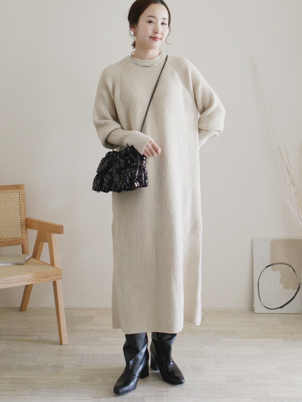 ベージュ系のワンピース、ブラック系のクラッチバッグ、ブラック系のブーツを着用したレディースの秋コーディネートの2枚目の写真