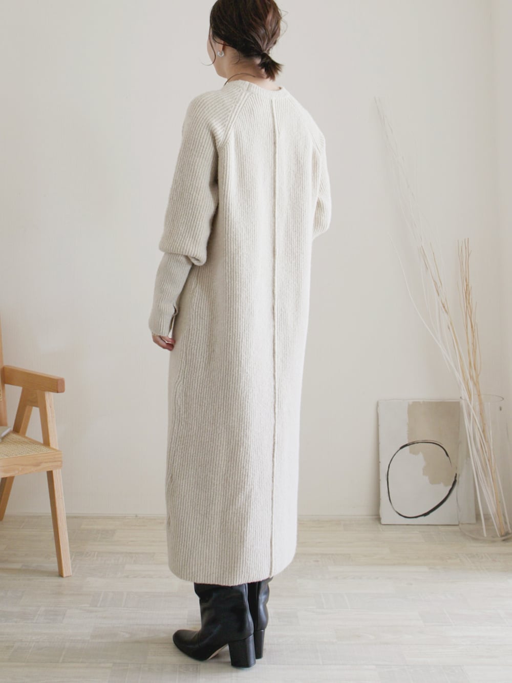 ベージュ系のワンピース、ブラック系のクラッチバッグ、ブラック系のブーツを着用したレディースの秋コーディネートの3枚目の写真