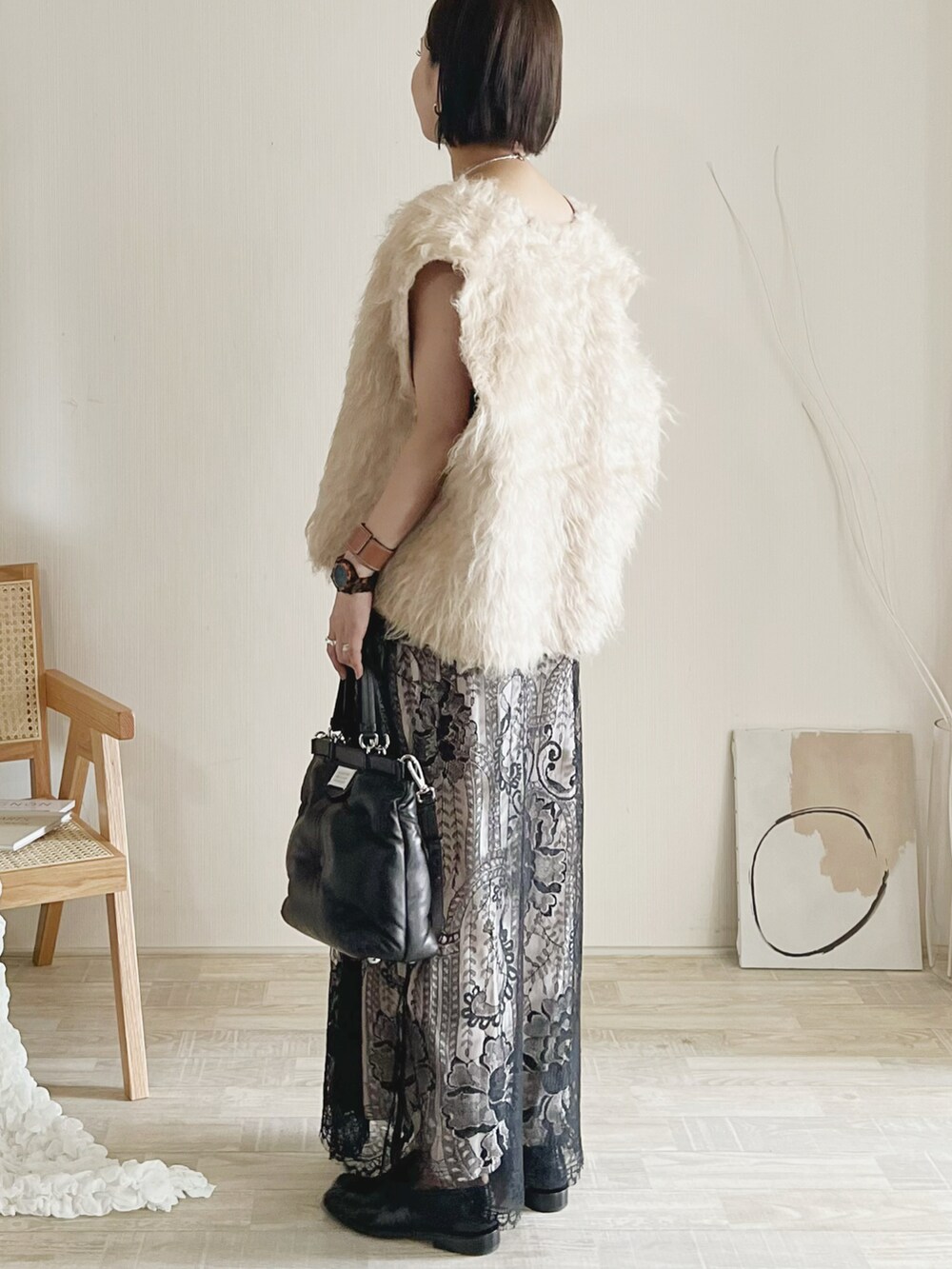 ベージュ系のベスト、ブラック系のスカート、ブラック系のショルダーバッグを着用したレディースの夏コーディネートの2枚目の写真