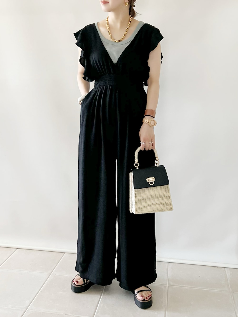 ブラック系のつなぎ/オールインワン、ブラック系のかごバッグ、ブラック系のサンダルを着用したレディースの夏コーディネートの2枚目の写真