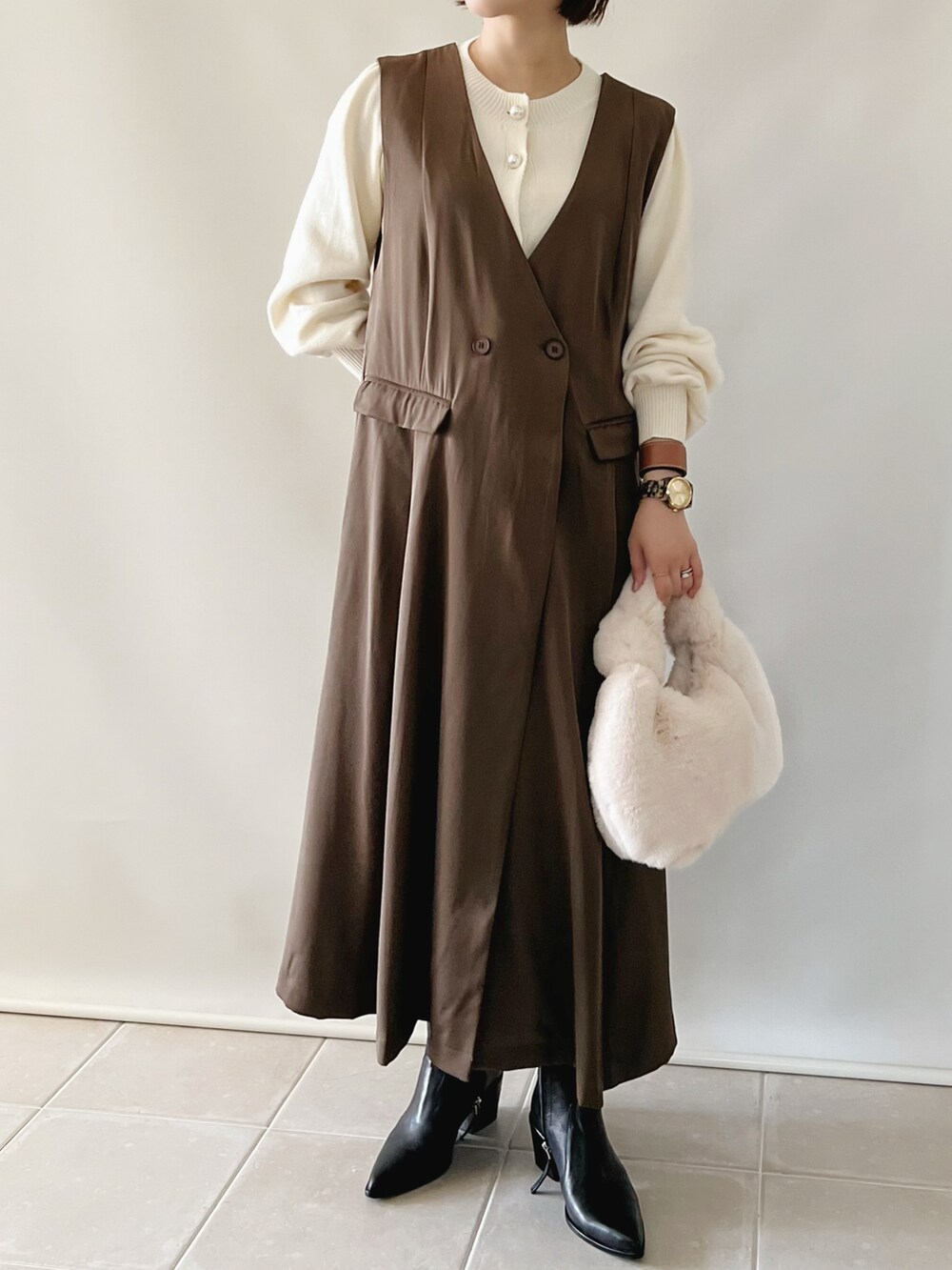 ブラウン系のジャンパースカート、ホワイト系のカーディガン/ボレロ、ホワイト系のバッグを着用したレディースの秋コーディネートの2枚目の写真