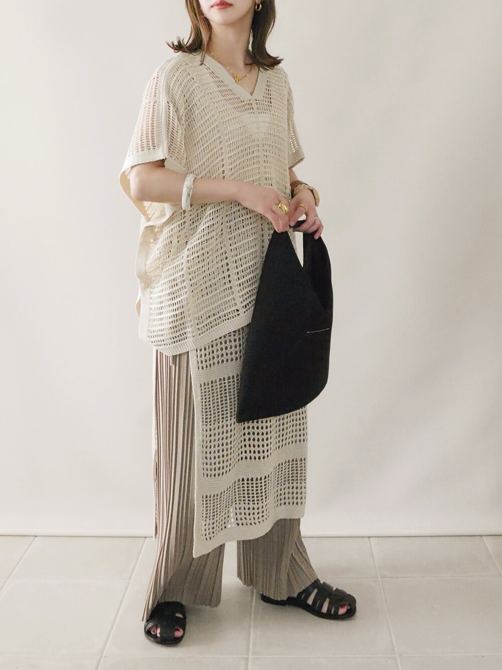 ベージュ系のニット/セーター、ベージュ系のワンピース、ブラック系のサンダルを着用したレディースの春コーディネートの2枚目の写真