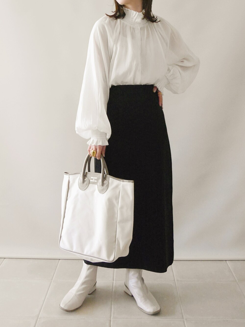 ベージュ系のトレンチコート、ホワイト系のシャツ/ブラウス、ブラック系のスカートを着用したレディースの春コーディネートの3枚目の写真