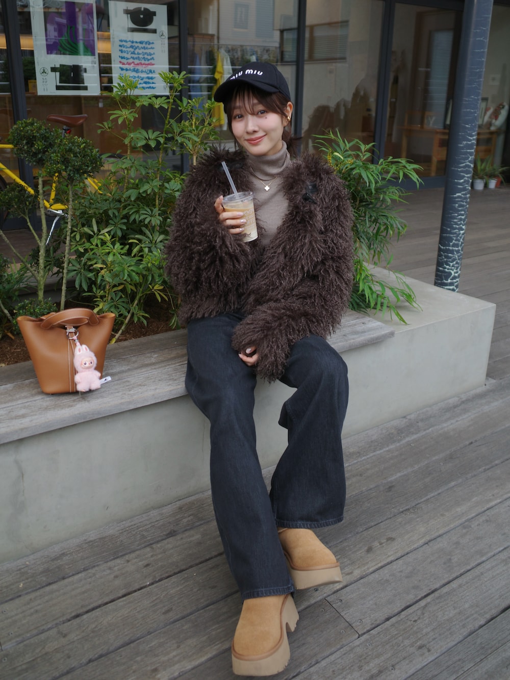 ブラック系のデニムパンツ、ベージュ系のブーツ、ブラウン系のハンドバッグを着用したレディースの冬コーディネートの2枚目の写真