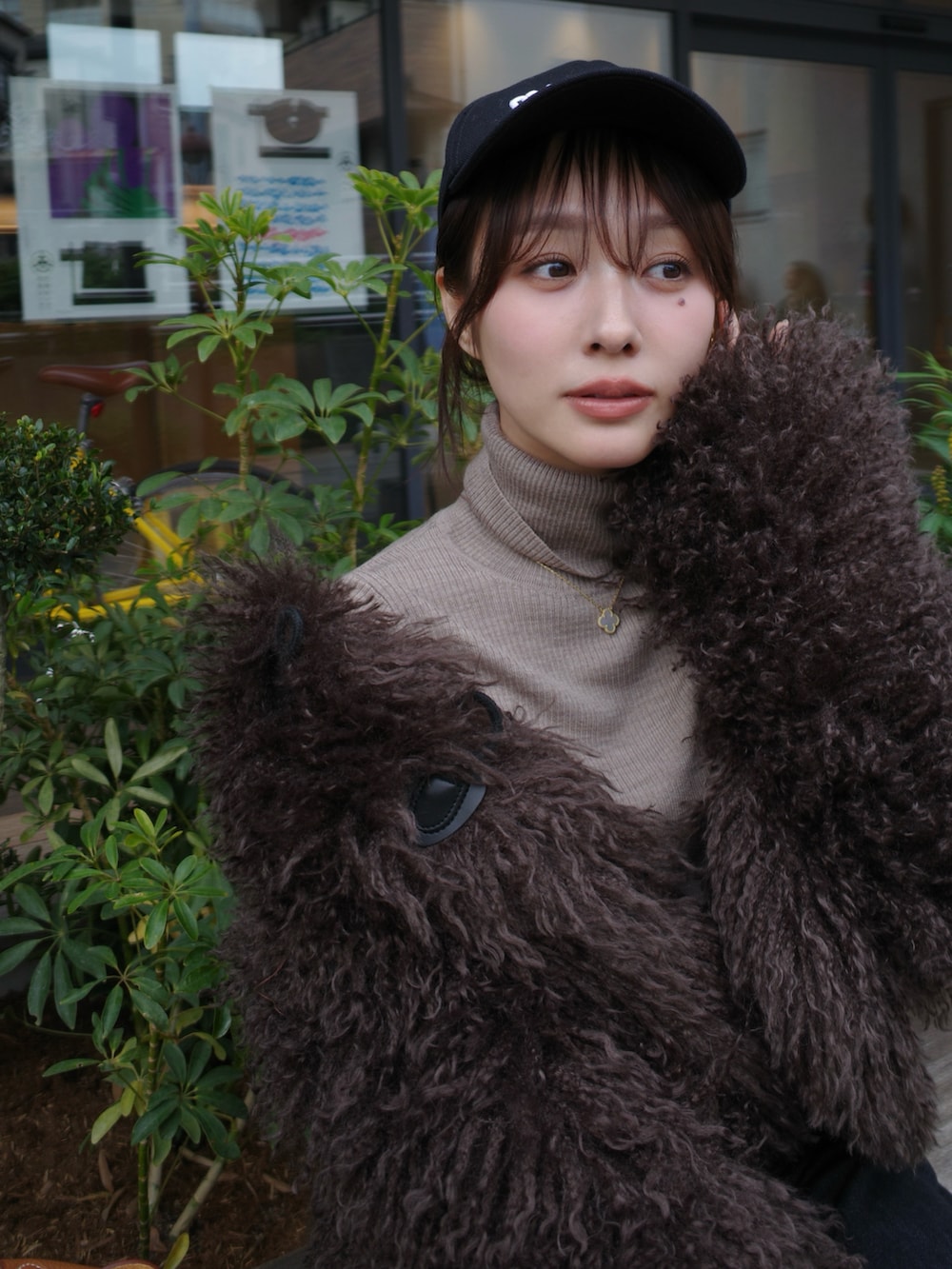 ブラック系のデニムパンツ、ベージュ系のブーツ、ブラウン系のハンドバッグを着用したレディースの冬コーディネートの4枚目の写真