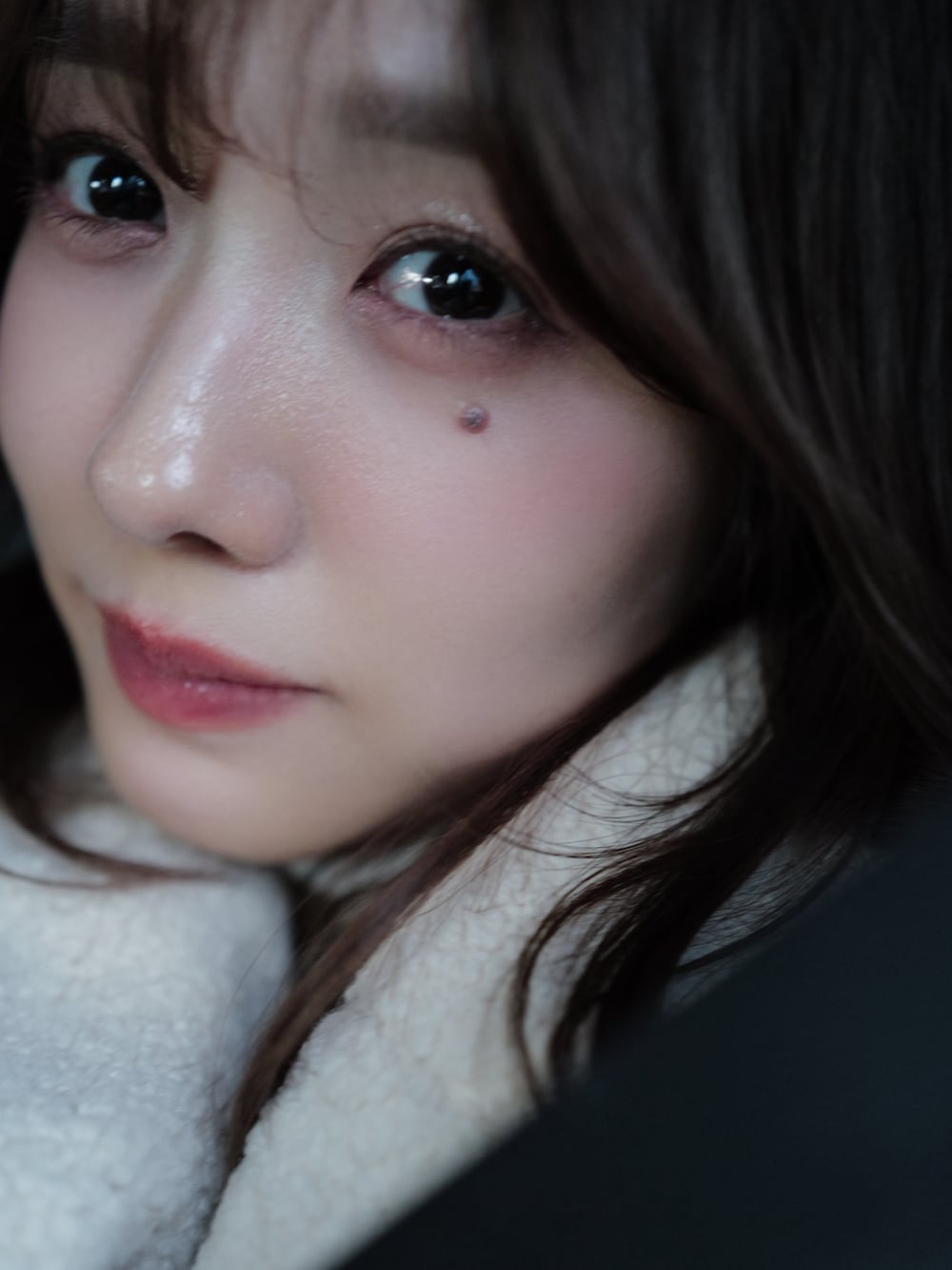 ホワイト系のチェスターコート、ホワイト系のニット/セーター、ブルー系のデニムパンツを着用したレディースの冬コーディネートの4枚目の写真